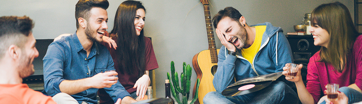 Happy friends having fun in home living room drinking and laughi